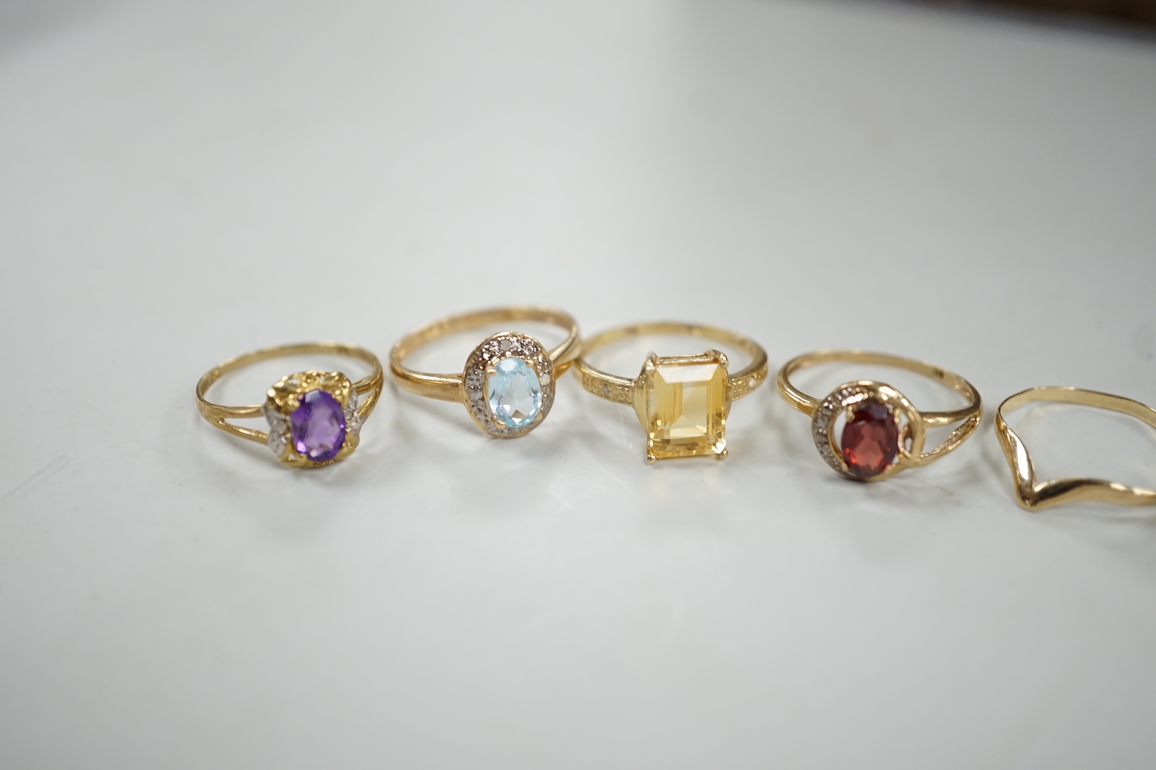 Five assorted modern 375 and gem set rings including amethyst and citrine, together with a 9ct wishbone shaped ring, gross weight 7.6 grams.